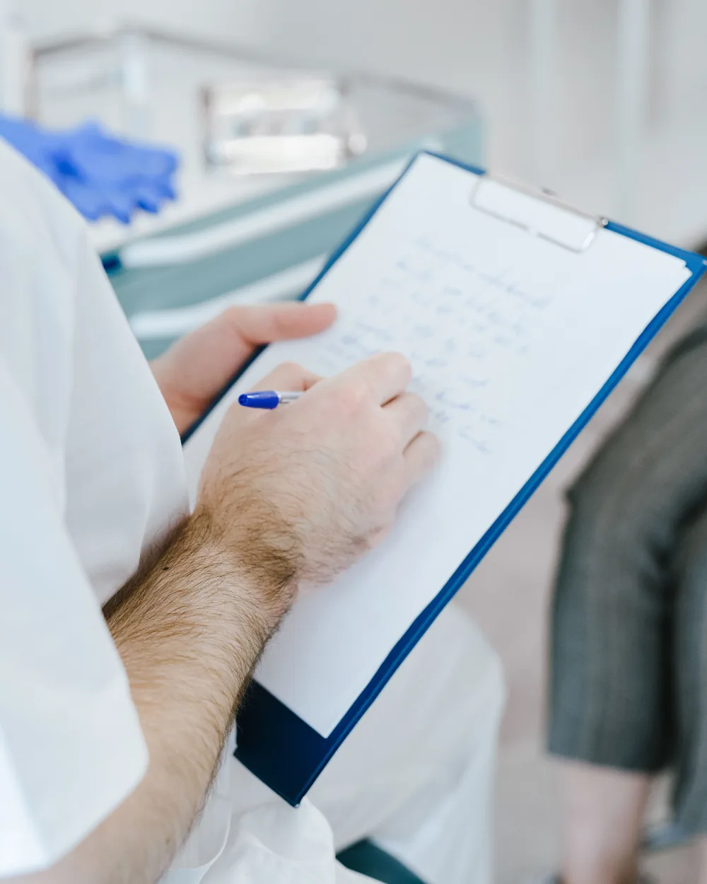 Clinician taking notes during a private health consultation
