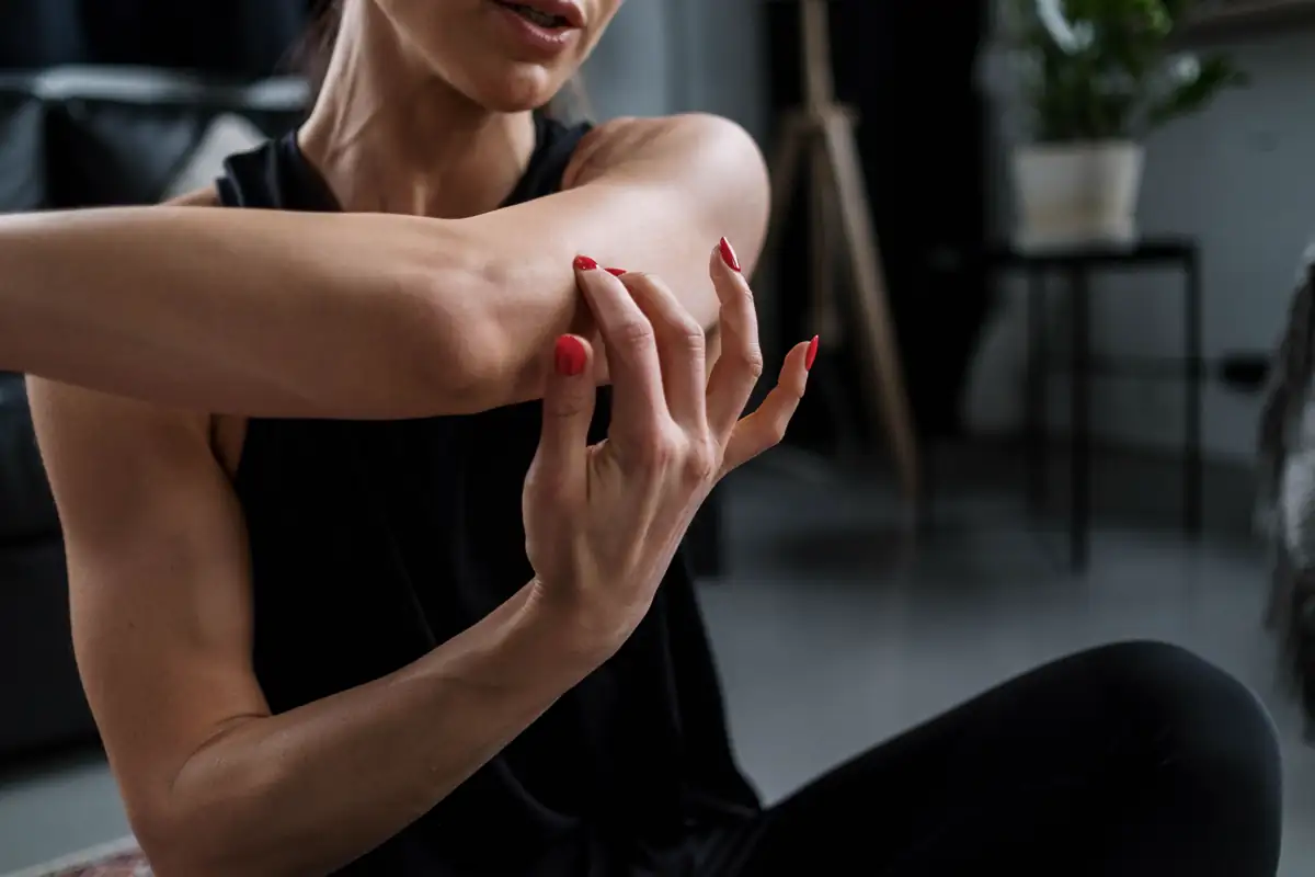 Woman stretching one arm across her chest during a home workout