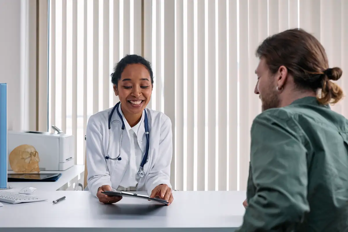 Doctor and patient talking across a desk in a bright clinic