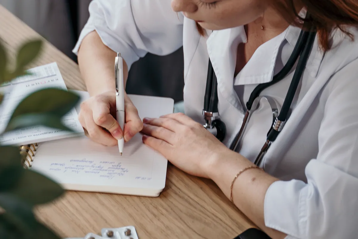 Clinician writing notes during a medical review
