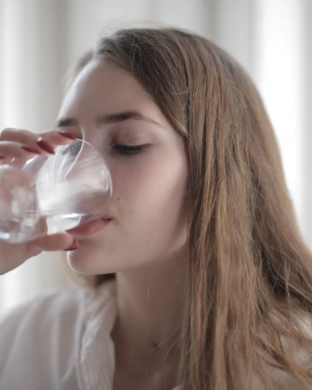 Adult drinking water from a clear glass indoors