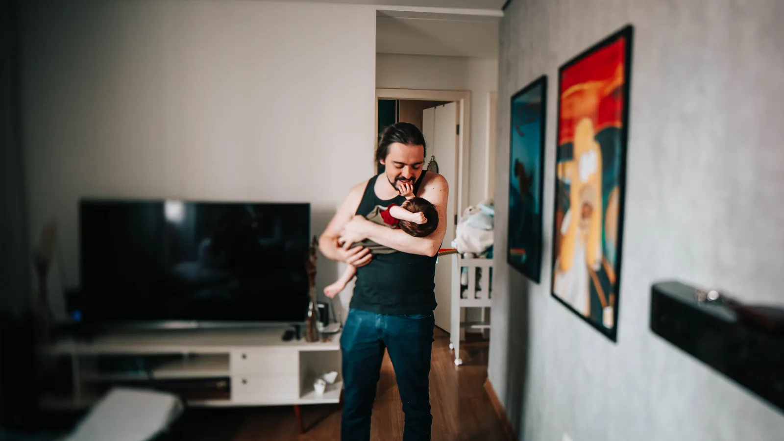 Father holding an infant in a living room