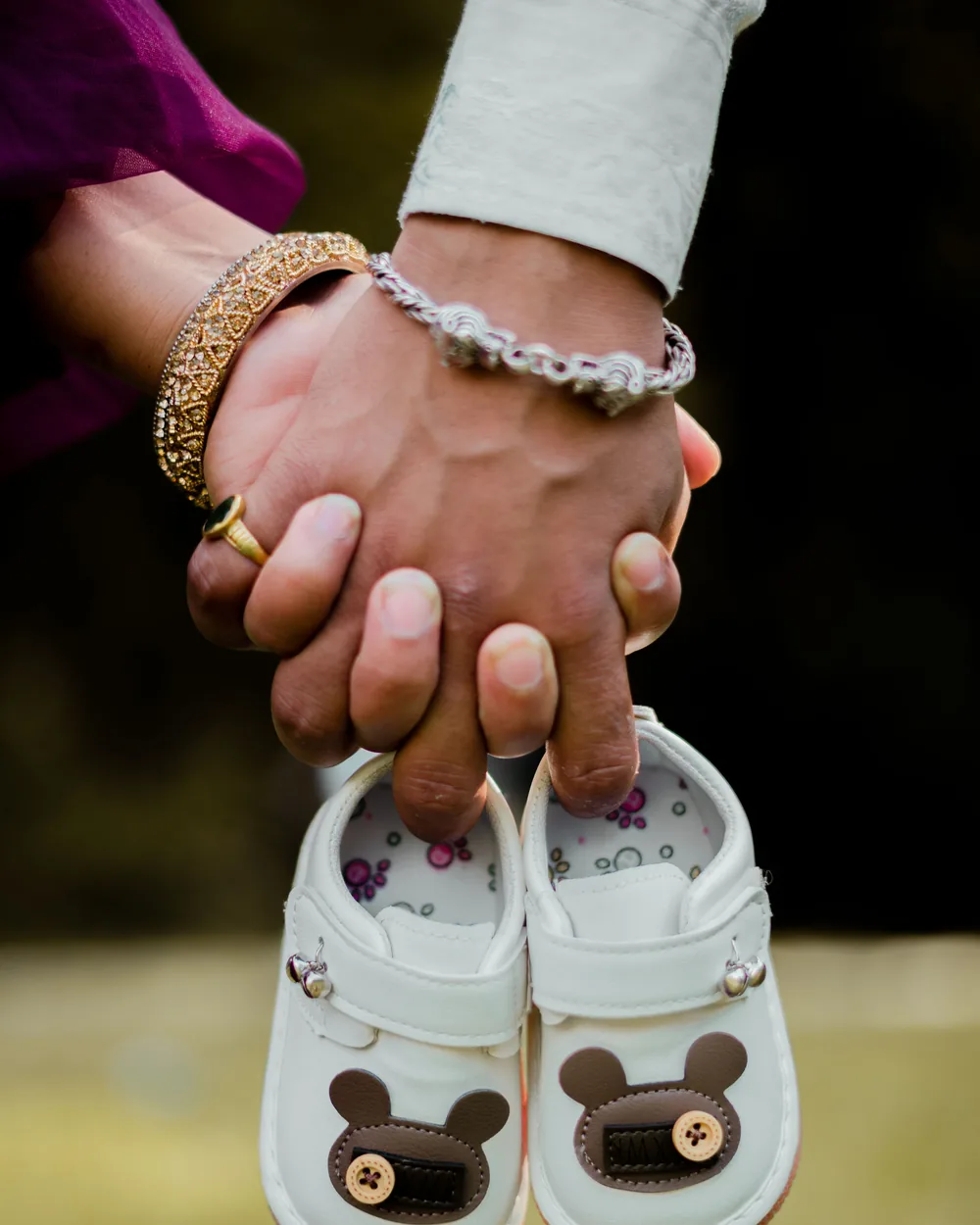 Couple holding hands with a pair of baby shoes