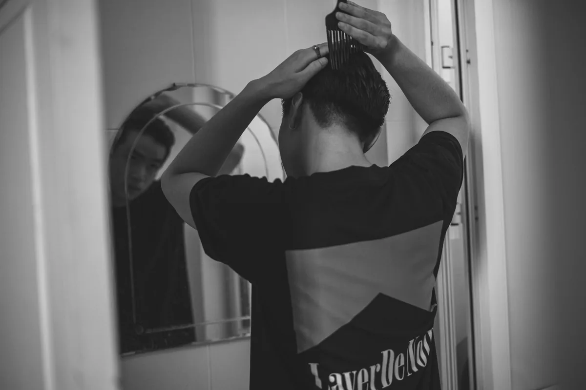Man combing his hair while looking into a round mirror